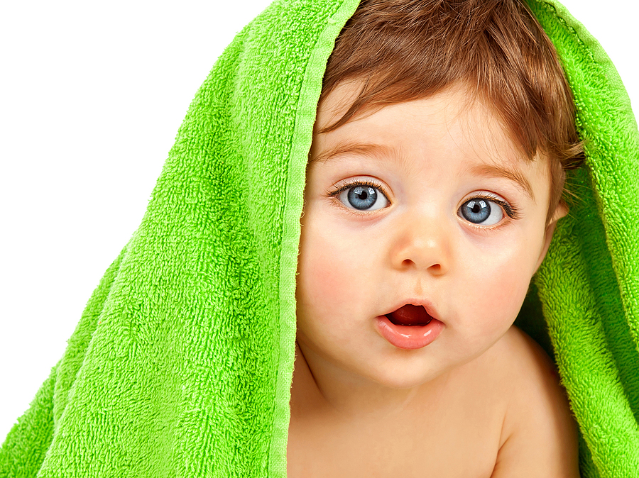 Image of cute baby boy covered with green towel isolated on whit